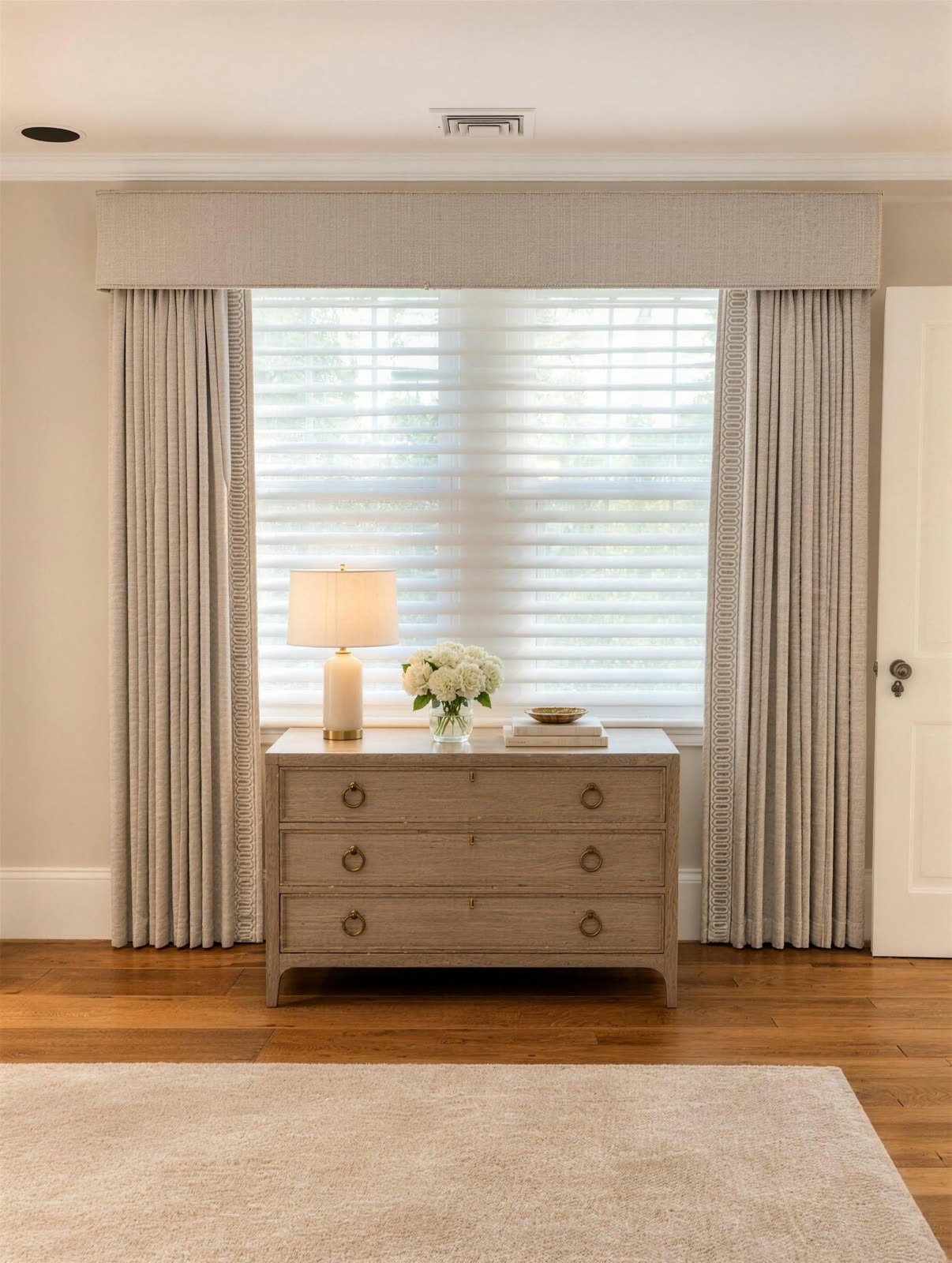 Custom upholstered box cornice over pleated drapery panels with banded edges and sheer shades