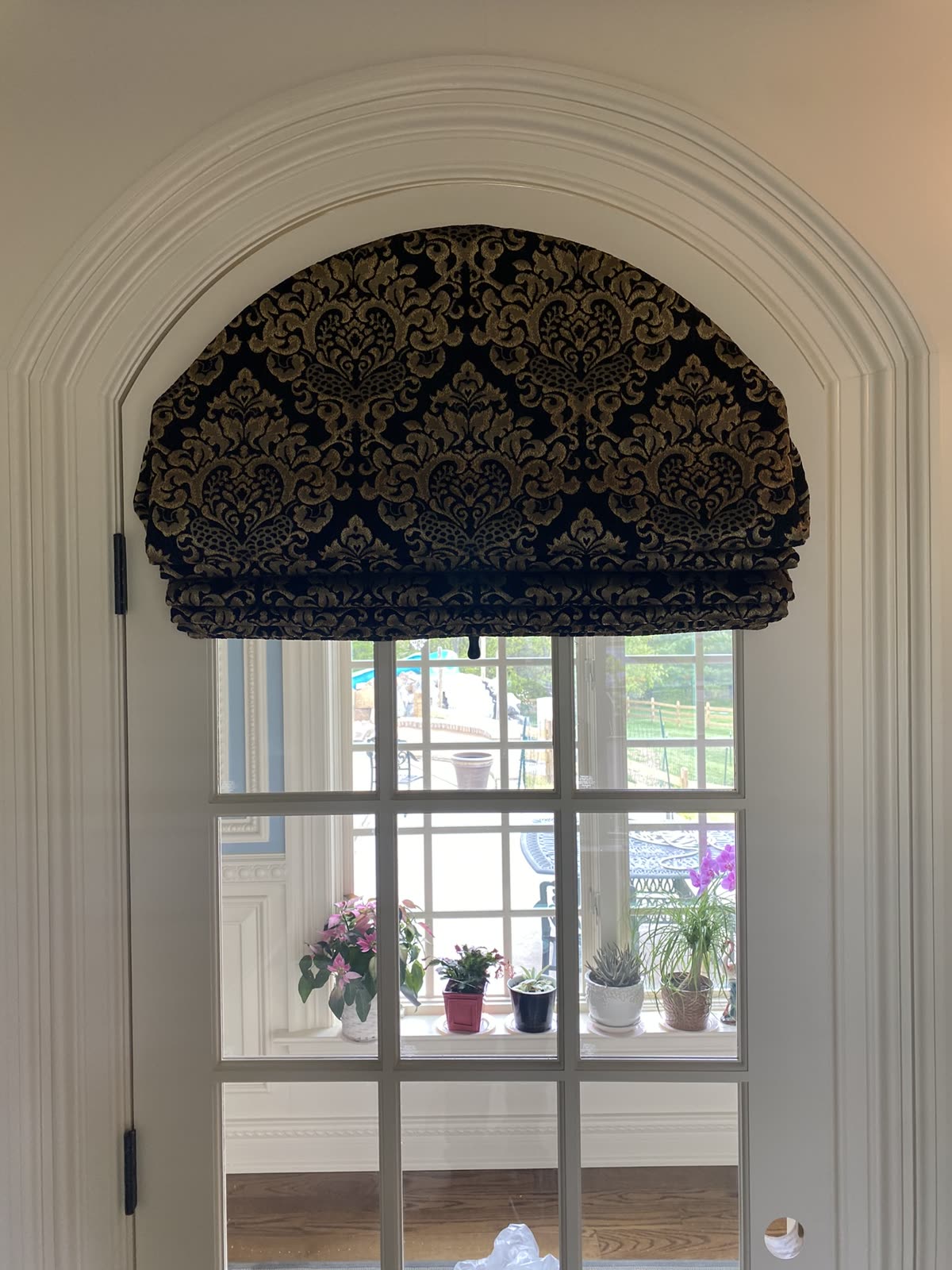 Arched Roman shade in a damask fabric over an arched French door, one of our installs