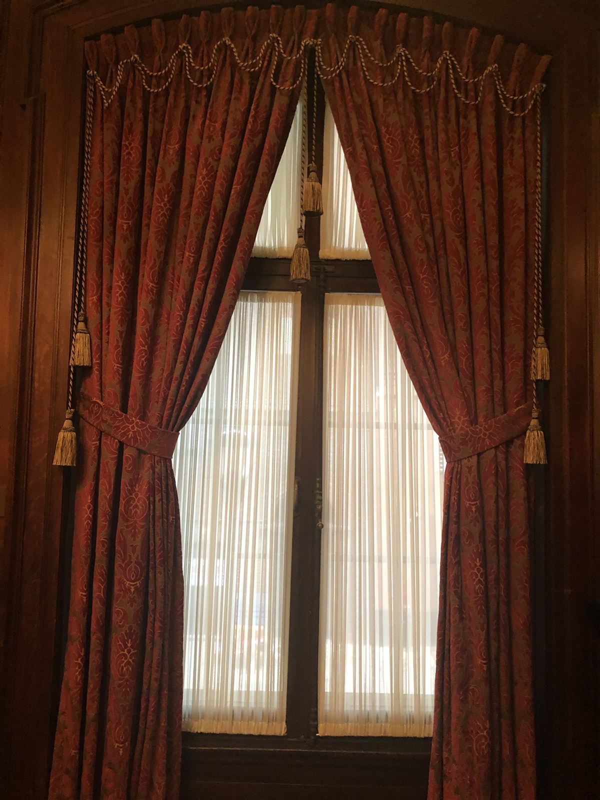 Damask drapery with rope trim and tasseled tiebacks