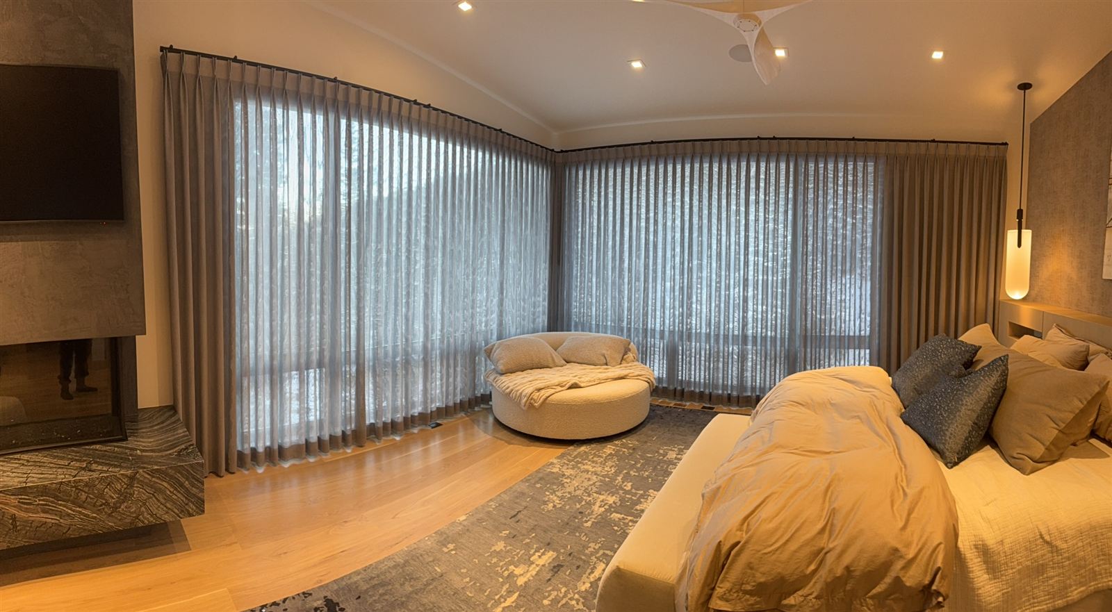 Floor-to-ceiling pleated sheers and drapery following a curved bedroom wall